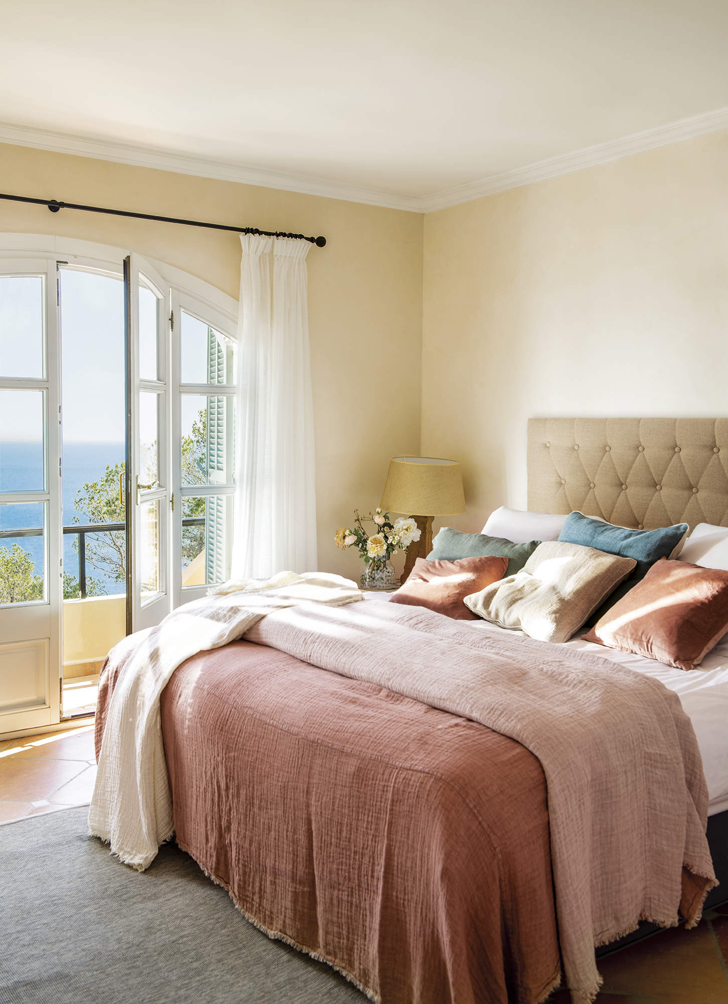 dormitorio con cabezal tapizado y ropa de cama rosa, alfombra gris
